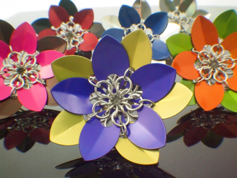 May include: A collection of colorful metal flowers with intricate designs. The flowers are made of metal and have a variety of colors, including pink, blue, yellow, orange, and green.