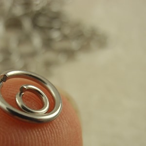 Puede incluir: Dos anillas de salto de metal plateado con forma circular y una peque&ntilde;a abertura en el alambre. Los anillos son lisos, pulidos y reflectantes, con un dise&ntilde;o sencillo de bucle abierto que se utiliza habitualmente para la joyer&iacute;a y ensamblaje.