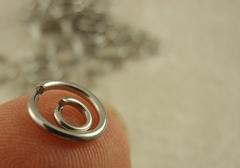 Puede incluir: Dos anillas de salto de metal plateado con forma circular y una peque&ntilde;a abertura en el alambre. Los anillos son lisos, pulidos y reflectantes, con un dise&ntilde;o sencillo de bucle abierto que se utiliza habitualmente para la joyer&iacute;a y ensamblaje.