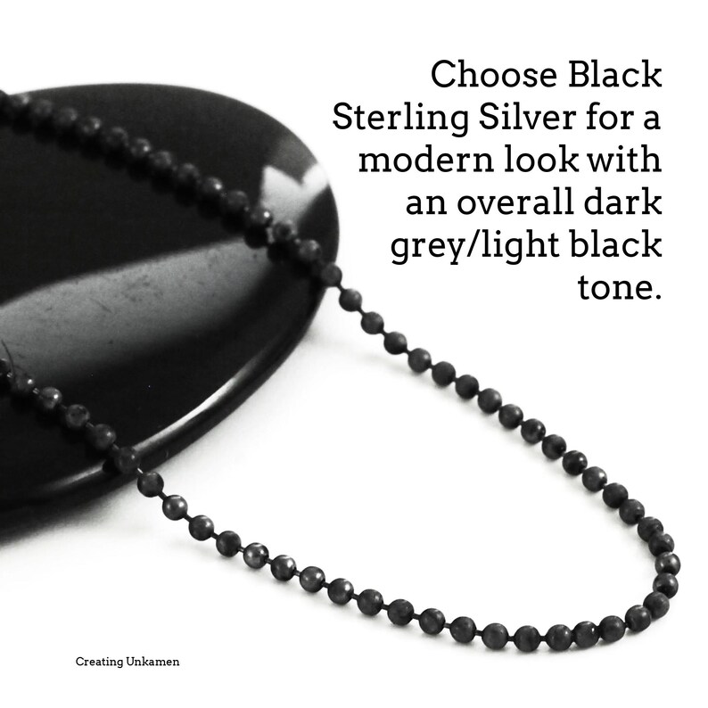 May include: A black sterling silver chain necklace with a ball chain design. The chain is on a black stone surface. Choose Black Sterling Silver for a modern look with an overall dark grey/light black tone.