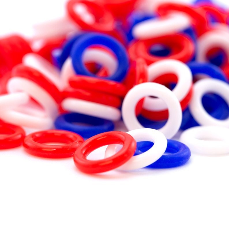 K&ouml;nnte beinhalten: Ein Stapel roter, wei&szlig;er und blauer Plastikringe. Die Ringe sind &uuml;bereinander gestapelt und in einem zuf&auml;lligen Muster angeordnet.