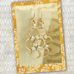 May include: Gold and silver chain earrings with a flower design. The earrings are made of interlocking circles.
