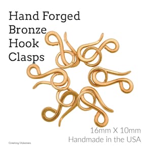 May include: Hand-forged bronze hook clasps, arranged in a circular pattern. Each clasp is a warm, golden color and has a unique, swirling design. The clasps measure 16mm x 10mm. Text on the image reads "Hand Forged Bronze Hook Clasps" and "Handmade in the USA."