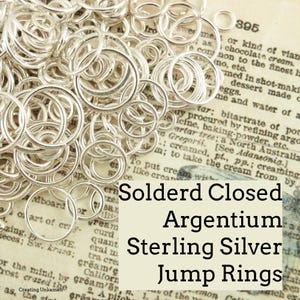 May include: A close-up of a pile of silver soldered closed jump rings. The rings are arranged in a random pattern and are all the same size. The text "Solderd Closed Argentium Sterling Silver Jump Rings" is superimposed on the image.