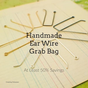 May include: Assortment of handmade ear wires in gold, silver, and black metal. The ear wires are arranged on a lined paper background. The text "Handmade Ear Wire Grab Bag At Least 50% Savings" is visible in the image.