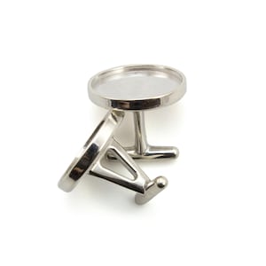 May include: A pair of silver cufflinks with round, clear glass inserts. The cufflinks are designed to be personalized with images or text.