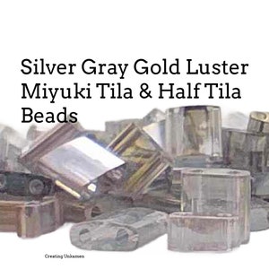 Könnte beinhalten: Silberne, graue und goldglänzende Miyuki Tila und Half Tila Perlen. Die Perlen sind auf einem weißen Hintergrund verstreut.