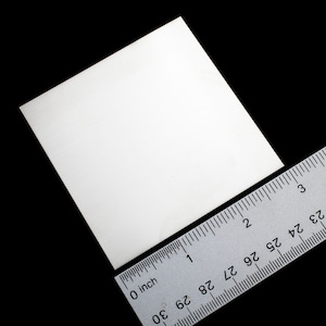 Op de afbeelding: Een wit vierkant stuk papier dat ongeveer 5 cm bij 5 cm meet, met een liniaal ernaast voor schaal.