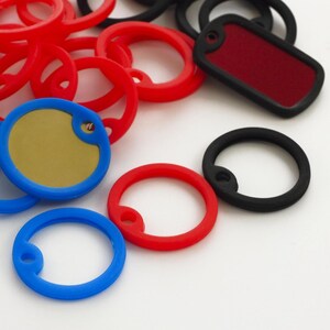 May include: Assortment of colorful key rings in red, blue, and black. The key rings are made of plastic and have a variety of shapes and sizes. Some of the key rings have a metal ring for attaching keys.