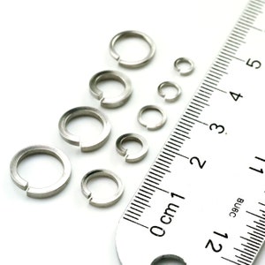 Puede incluir: Surtido de anillos de salto de metal plateado de diferentes tama&ntilde;os, medidos con una regla en cent&iacute;metros.