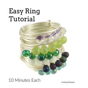 Può includere: Primo piano di una pila di anelli d'argento con perline colorate. Gli anelli sono decorati con perline verdi, blu, viola e bianche. Il testo "Easy Ring Tutorial" e "10 Minutes Each" è visibile nell'immagine.