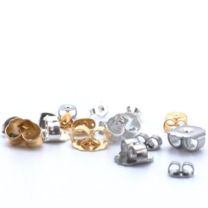 May include: Assortment of earring backs in gold, silver, and platinum finishes. The backs are made of metal and have a butterfly closure.