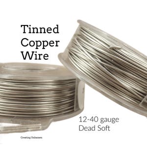 Peut inclure: Deux bobines en plastique transparent contenant du fil de cuivre étamé de couleur argentée. Le texte sur l'image indique Tinned Copper Wire et 12-40 gauge Dead Soft, avec la marque Creating Unkamen en bas. Le fil est enroulé autour des bobines.