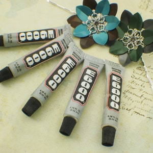 May include: Five tubes of E6000 industrial strength adhesive, each with a black cap and a silver label with the text "E6000 Industrial Strength" and "0.18 fl oz (5.32 ml)".