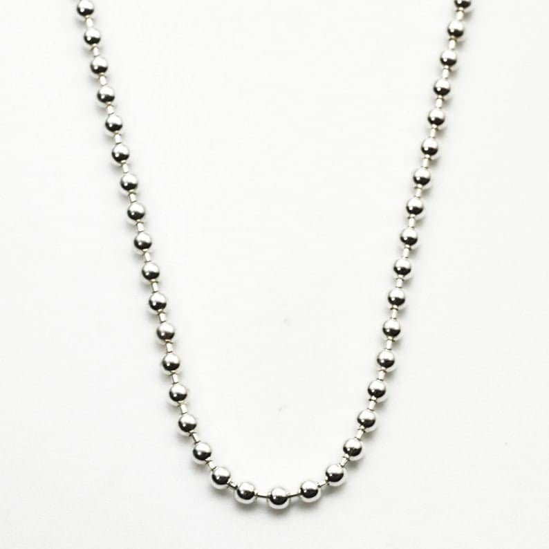 May include: A silver ball chain necklace. The chain is made of small, round beads.