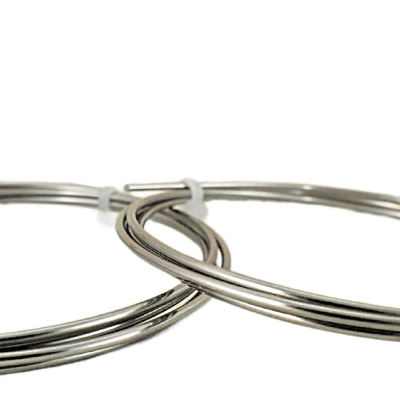 May include: Close-up of three silver-colored metal wires coiled together. The wires are round and smooth.