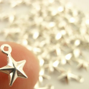 May include: Silver star charm with a loop for attaching to jewelry or crafts. The star is five-pointed and has a slightly raised center.