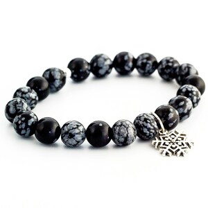 May include: Black and white snowflake obsidian beaded bracelet with a silver snowflake charm.