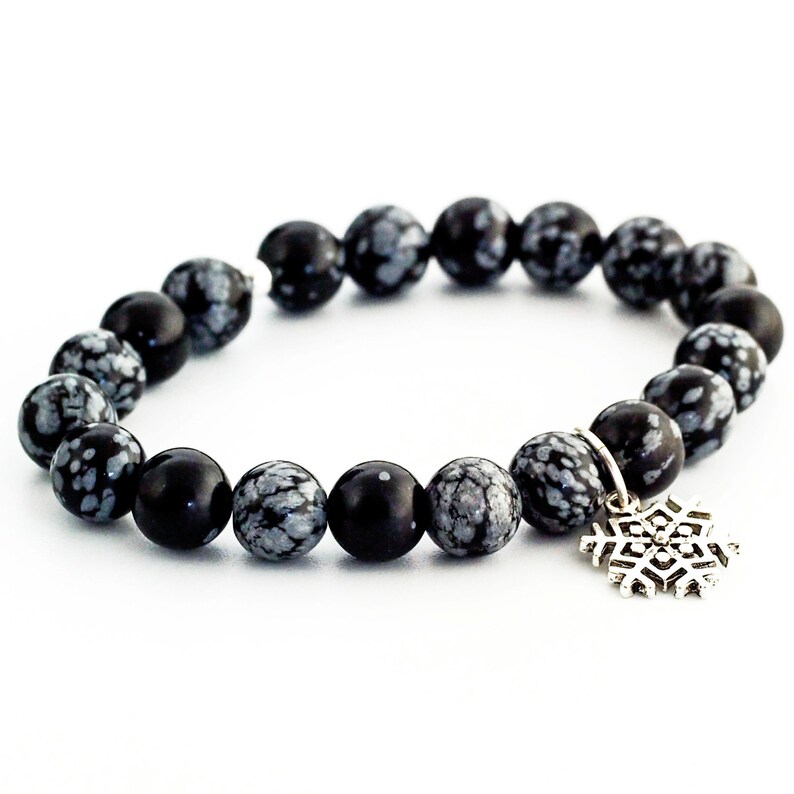May include: Black and white snowflake obsidian beaded bracelet with a silver snowflake charm.