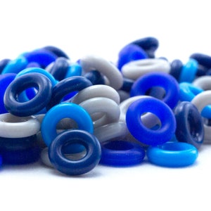 K&ouml;nnte beinhalten: Ein Haufen bunter Plastikringe in Blaut&ouml;nen und Grau. Die Ringe sind alle gleich gro&szlig; und gleich geformt und in einem zuf&auml;lligen Muster angeordnet.