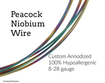 Puede incluir: Alambre de niobio Peacock, anodizado personalizado, 100% hipoalergénico, calibre 8-28. El alambre presenta un acabado iridiscente multicolor con tonos cambiantes de oro, verde, azul y morado, dispuestos en tres hebras paralelas curvas.