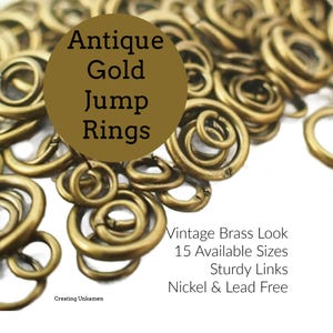 以下が含まれることがあります： 円形のアンティークゴールドカラーの丸カン。画像内のテキストは「Antique Gold Jump Rings」「Vintage Brass Look」「15 Available Sizes」「Sturdy Links」「Nickel & Lead Free」「Creating Unkamen」と記載されています。