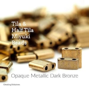 May include: A close-up of a pile of opaque metallic dark bronze Tila and Half Tila Miyuki beads. The beads are small and rectangular with two holes in each.
