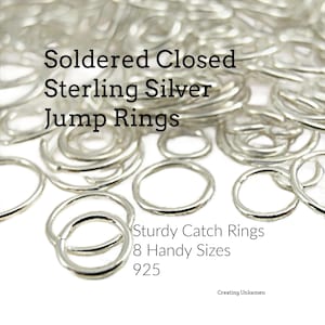 May include: A collection of shiny silver jump rings with the text Soldered Closed Sterling Silver Jump Rings, Sturdy Catch Rings, 8 Handy Sizes, 925, and Creating Unkamen. These circular metal rings are scattered in various sizes and diameters.