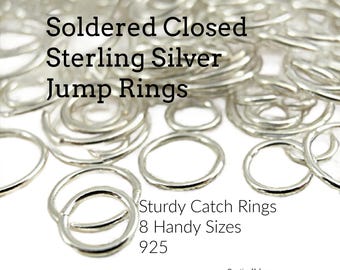 May include: A collection of shiny silver jump rings with the text Soldered Closed Sterling Silver Jump Rings, Sturdy Catch Rings, 8 Handy Sizes, 925, and Creating Unkamen. These circular metal rings are scattered in various sizes and diameters.