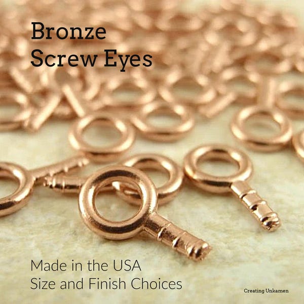 May include: A close-up of a pile of bronze screw eyes. The screw eyes are small and have a round loop at the top. The screw eyes are made in the USA. Size and finish choices are available.  Made in the USA. Size and Finish Choices.