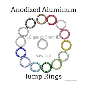 Puede incluir: Anillas de salto de aluminio anodizado dispuestas en círculo con una en el centro. Las anillas son de varios colores, incluyendo rojo, rosa, oro, verde, azul, morado y plata. Texto: Anodized Aluminum, 18 gauge 5mm ID, Saw Cut, Jump Rings.