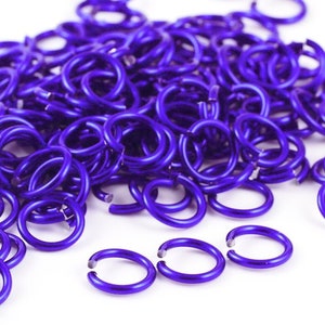 May include: A large pile of small, purple metal jump rings. The rings are all the same size and are arranged in a random pattern.
