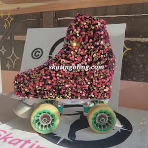 May include: A black roller skate boot with a pink, orange, and green sequin cover. The boot is on a white surface with the text "skatingbling.com" and "VARIANT" on the boot.
