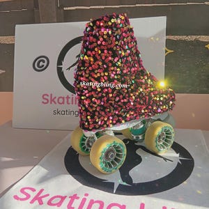 May include: Pink, black, and gold roller skate boot with sequins. The boot is on a white surface with a black circle and the text "skatingbling.com".