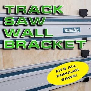 May include: A wall-mounted track saw bracket with the text "TRACK SAW WALL BRACKET" in green letters and "FITS ALL POPULAR SAWS!" in yellow. The bracket is made of metal and has a blue and silver finish. The text "Makita" is visible on the bracket.