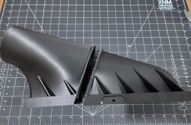 May include: Two black 3D printed parts with a geometric design. The parts are made of a smooth, matte black plastic. The parts are designed to be joined together.