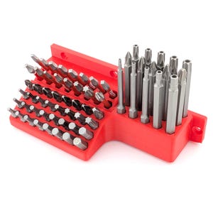 May include: A red plastic organiser containing a variety of silver and black screwdriver bits. The bits are arranged in rows and columns, with different shapes and sizes. The organiser has mounting holes.
