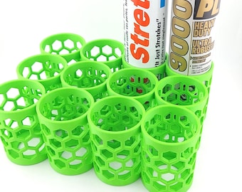 May include: A collection of bright green, honeycomb-patterned holders, possibly for construction adhesive tubes. Two tubes of adhesive are visible, one labeled "Stretch" and the other "PL 9000". The holders are arranged in a grid, suggesting organization and storage.