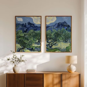 May include: Two framed art prints of a landscape with olive trees under a blue sky with clouds. The artwork uses greens, blues, and yellows, with visible brushstrokes. The frames are a warm brown colour. The prints are reminiscent of Van Gogh.