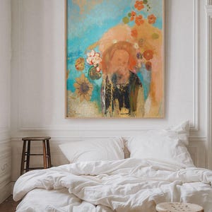 May include: Abstract art print in a wooden frame. The artwork features a figure with a beard, surrounded by flowers in shades of orange, yellow, and red against a blue and peach background. The painting hangs above a bed with white linens.