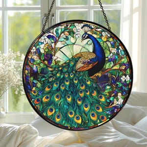 May include: A round stained glass window featuring a peacock with a vibrant display of blue, green, and gold feathers. The peacock is surrounded by colorful floral and foliage elements, set against a light green background. The window is framed in black and suspended by a chain.