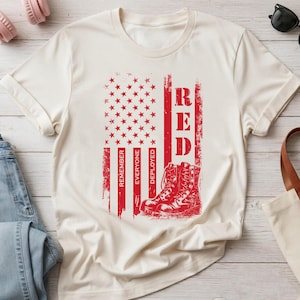 Könnte beinhalten: Ein cremefarbenes Kurzarm-T-Shirt mit einer roten Grafik einer stilisierten amerikanischen Flagge mit Sternen und Streifen. Das Design enthält den Text "REMEMBER EVERYONE DEPLOYED" und "RED" sowie die Abbildung eines Paars Militärstiefel.