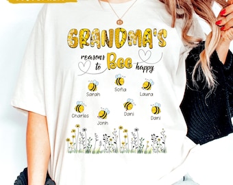 May include: White t-shirt with a bee-themed design that says "Grandma's reasons to bee happy" with a list of names below the text. The names are: Sofia, Sarah, Laura, Charles, Dani, Dani, and Jonh.