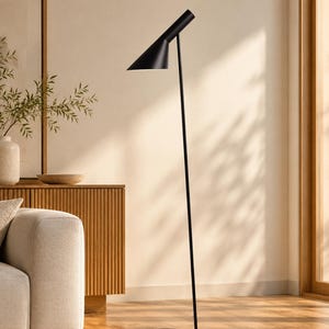 May include: A matte black floor lamp featuring a slender vertical pole, a circular base with an open center, and an adjustable conical shade that directs light downward. The lamp has a clean, streamlined silhouette with a simple metal construction.