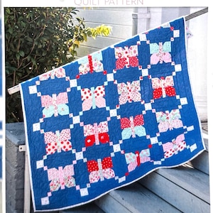 May include: A quilt pattern titled Flitter Quilt Pattern featuring a blue quilt with a repeating butterfly motif in red, pink, and white floral and polka dot fabrics. The cover includes the text Sew Sampler Exclusive and Bonus Size Option Included.