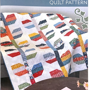 May include: A quilt pattern titled "Spring Ivy" with a colorful patchwork design. The quilt features geometric shapes in various colors, including red, blue, yellow, and green, on a white background. Finished size is 50 ½" x 57 ½".