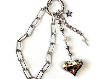 May include: A silver chain keychain with a heart charm, a pearl bead, and star and lightning bolt charms.