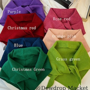 Pode incluir: Uma coleção de cachecóis coloridos e atados em várias tonalidades, incluindo roxo, vermelho rosa e verde-grama. Cada cachecol é rotulado com o nome da sua cor. O texto "@Dewdrop Macket" é visível na parte inferior.
