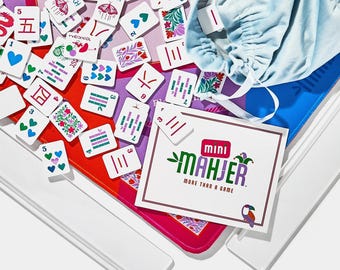 May include: A Mini Mahjer game set featuring white tiles with colorful illustrations of butterflies, hearts, flowers, and Chinese characters. Includes a light blue drawstring storage bag, two white plastic tile racks, and a game instruction card.