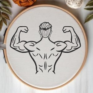 Puede incluir: Un bastidor de bordado con un dibujo lineal negro de una figura musculosa flexionando sus bíceps. El diseño está centrado en tela blanca, dentro de un bastidor de madera. La figura se ve desde atrás, mostrando músculos definidos.